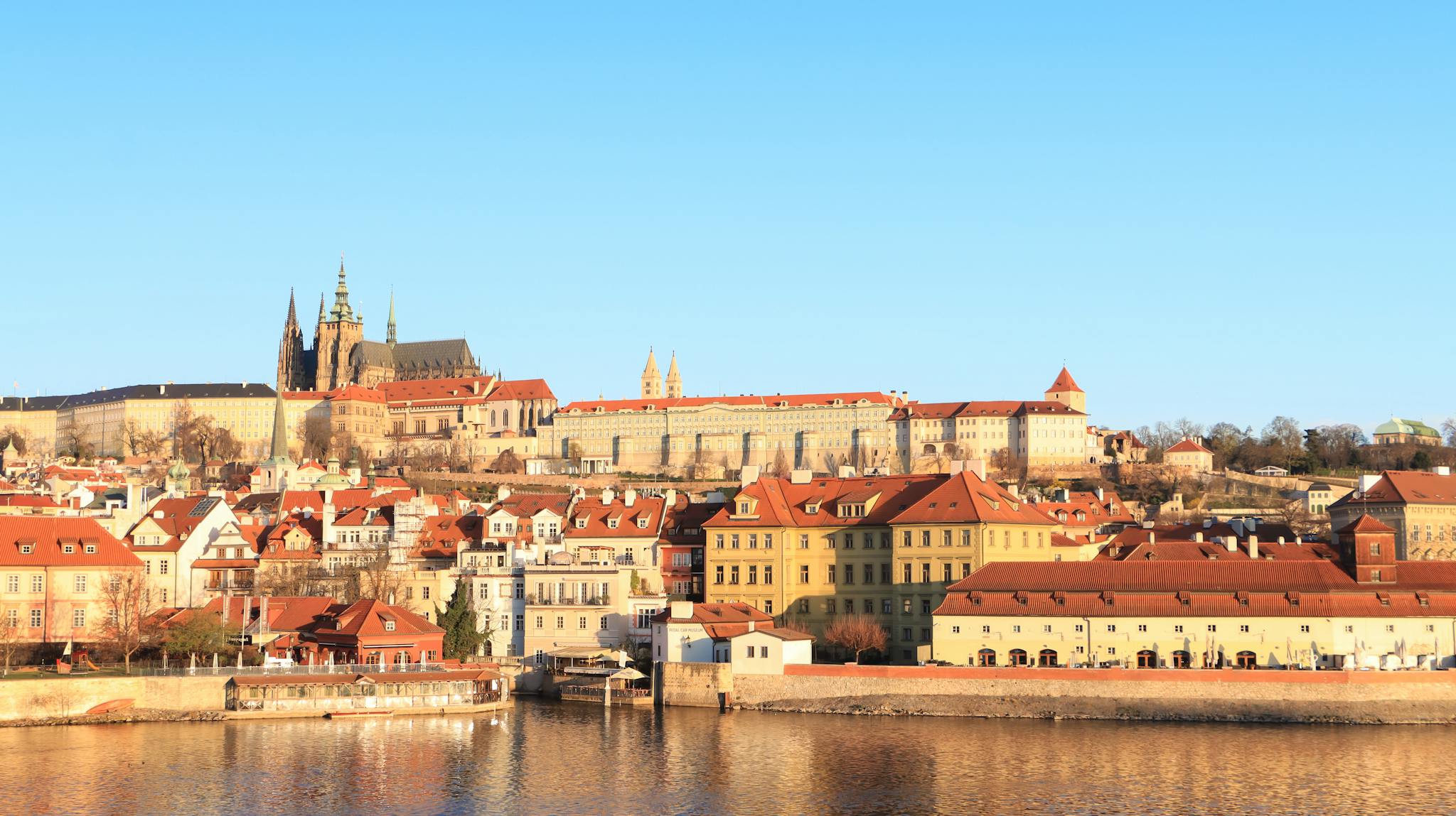 Beautiful panoramic view of Prague Castle and surrounding architecture under warm sunlight.